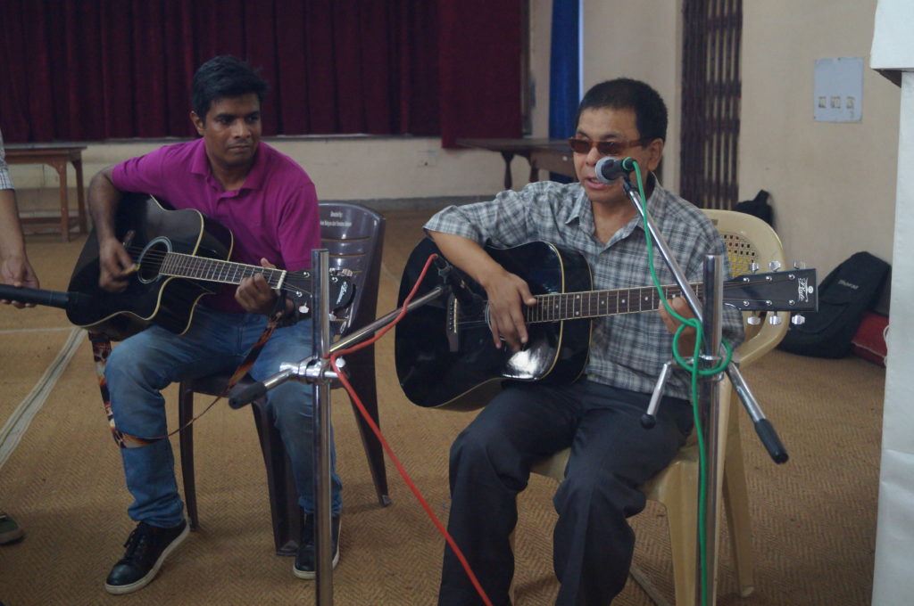 Trainee Bharat singing and playing guitar along with a mentor from HSBC